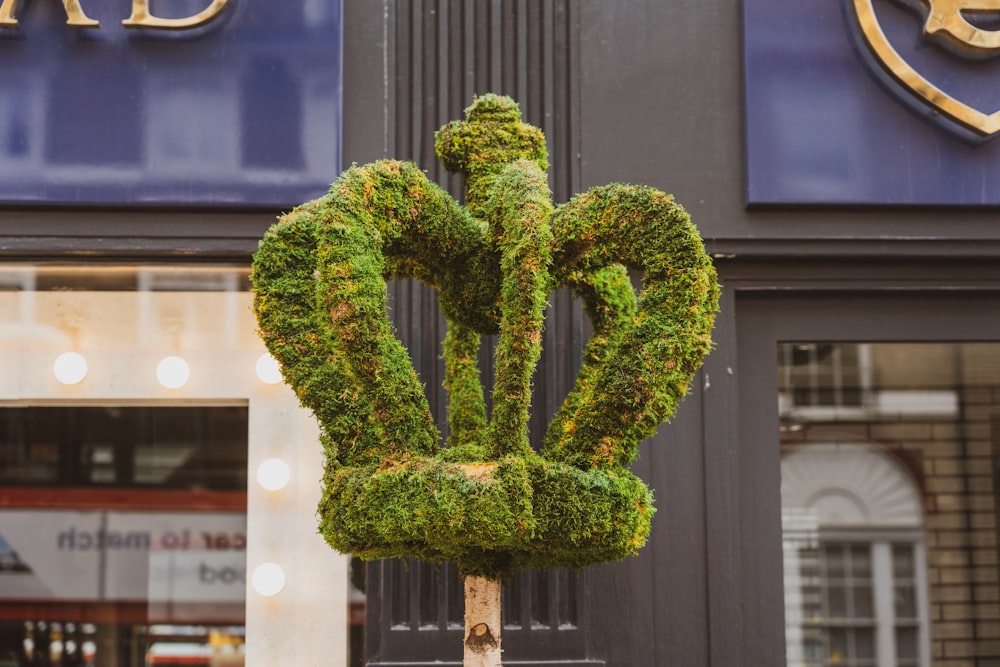 Una escultura verde de una flor en un poste frente a una tienda