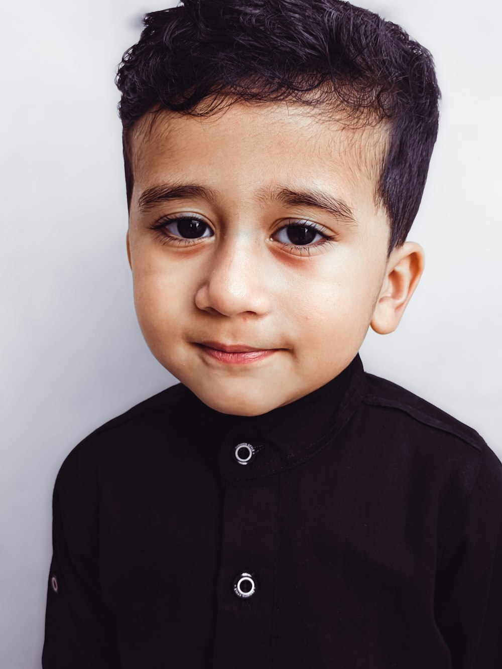 a young boy with a black shirt and black hair