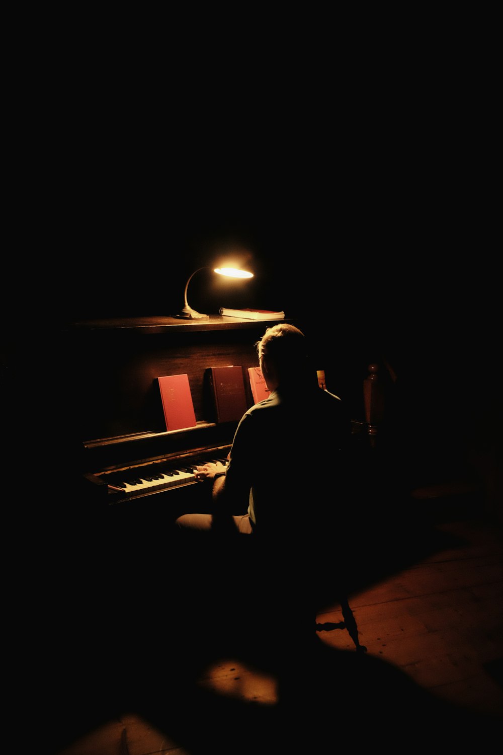 a man sitting at a piano in the dark