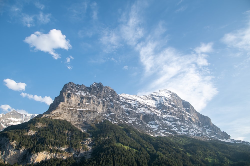 a mountain with snow on it and a few clouds in the sky