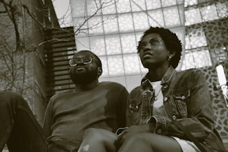 Two friends sitting apart, showing tension and misunderstanding in their body language.