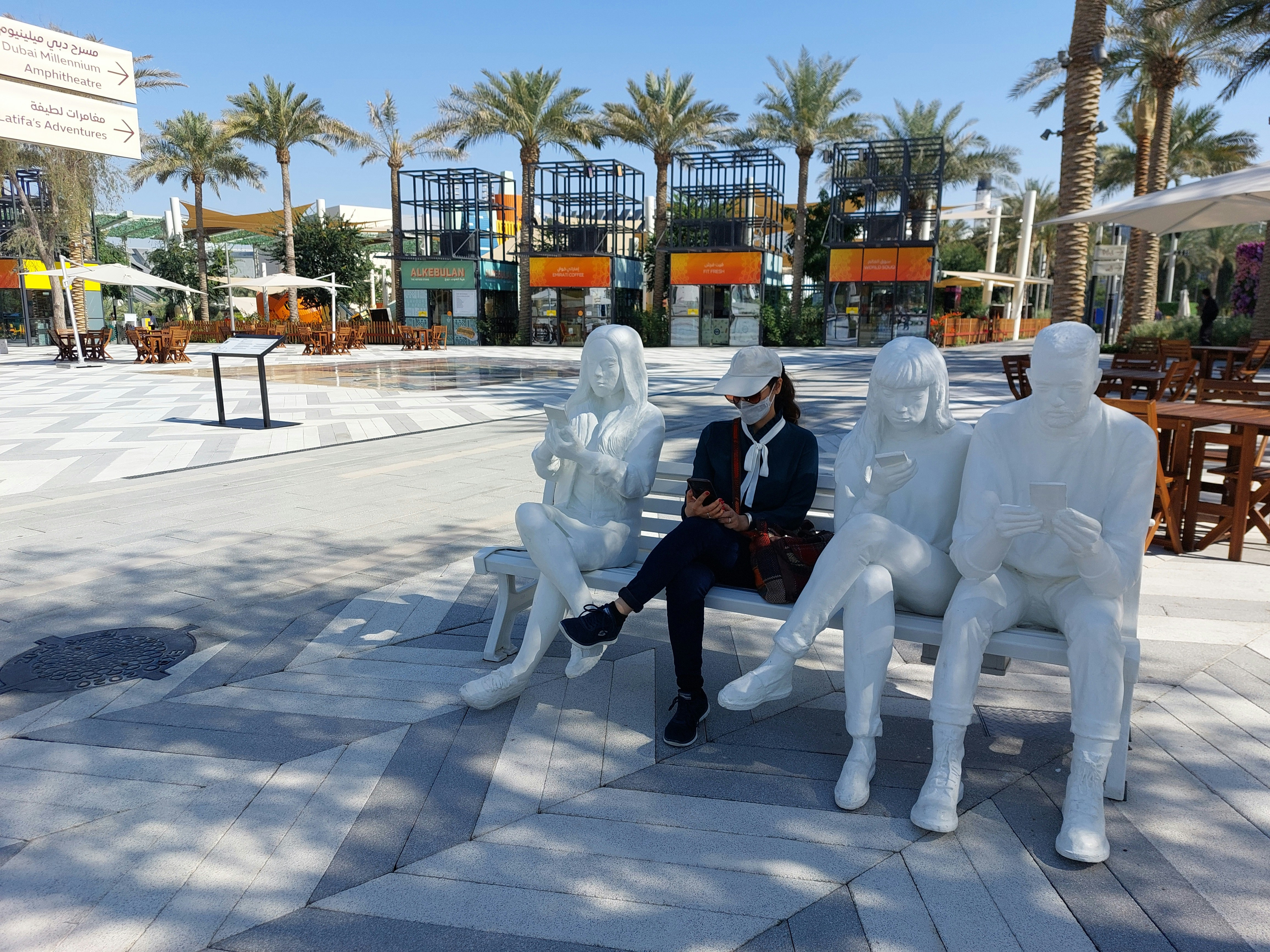 a woman sitting on a bench in front of a sculpture