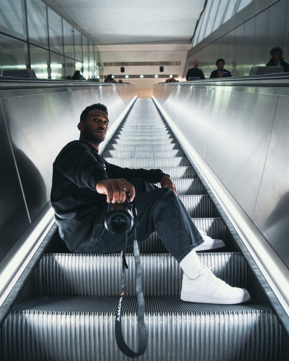 a man sitting on an escalator with a camera