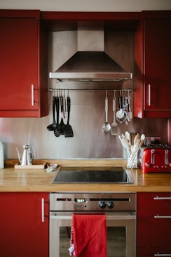 a kitchen with red cabinets and stainless steel appliances