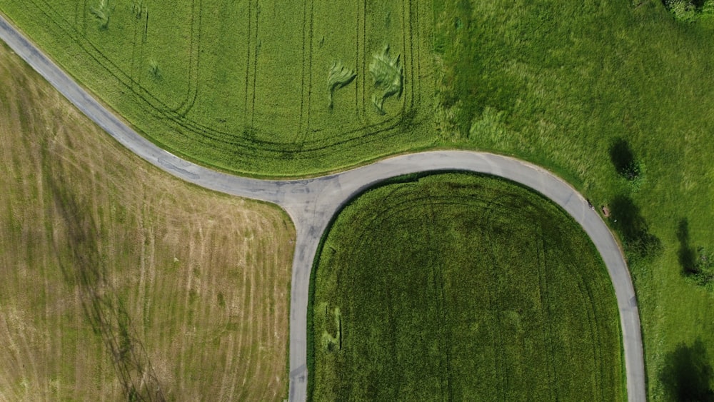 an aerial view of a winding road in a green field