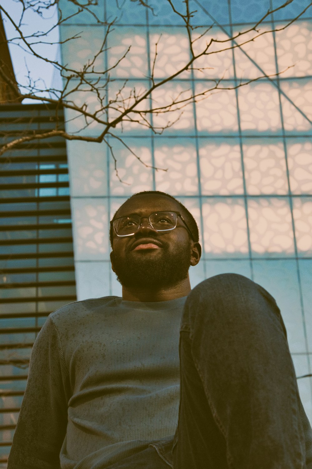 a man with a beard and glasses standing in front of a building