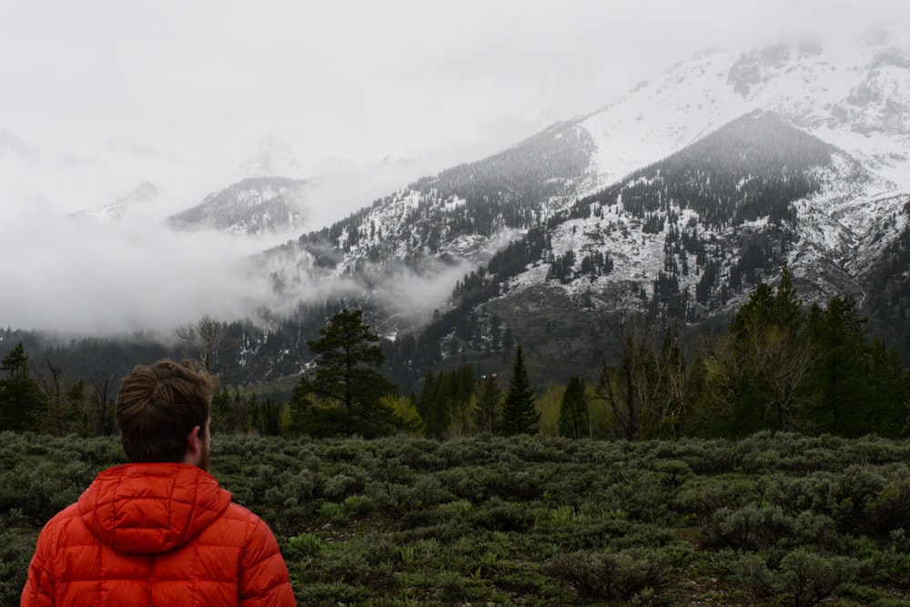 a person in a red jacket looking at a mountain