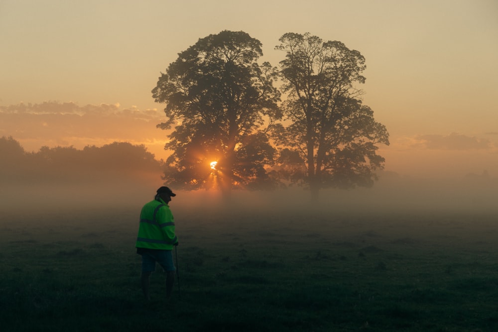 a man standing in a field at sunset