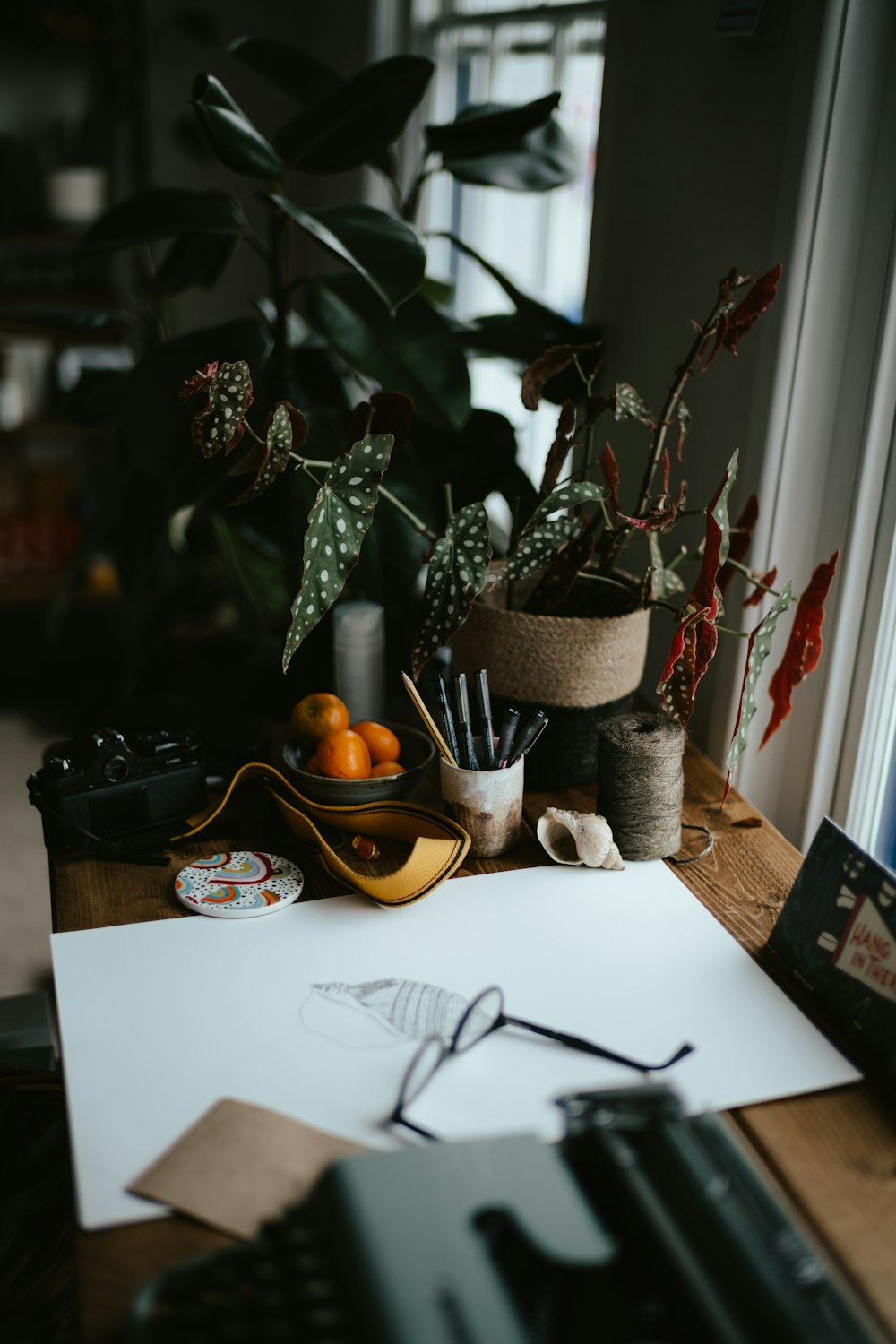 a picture of a desk with a pen, oranges, glasses, and a