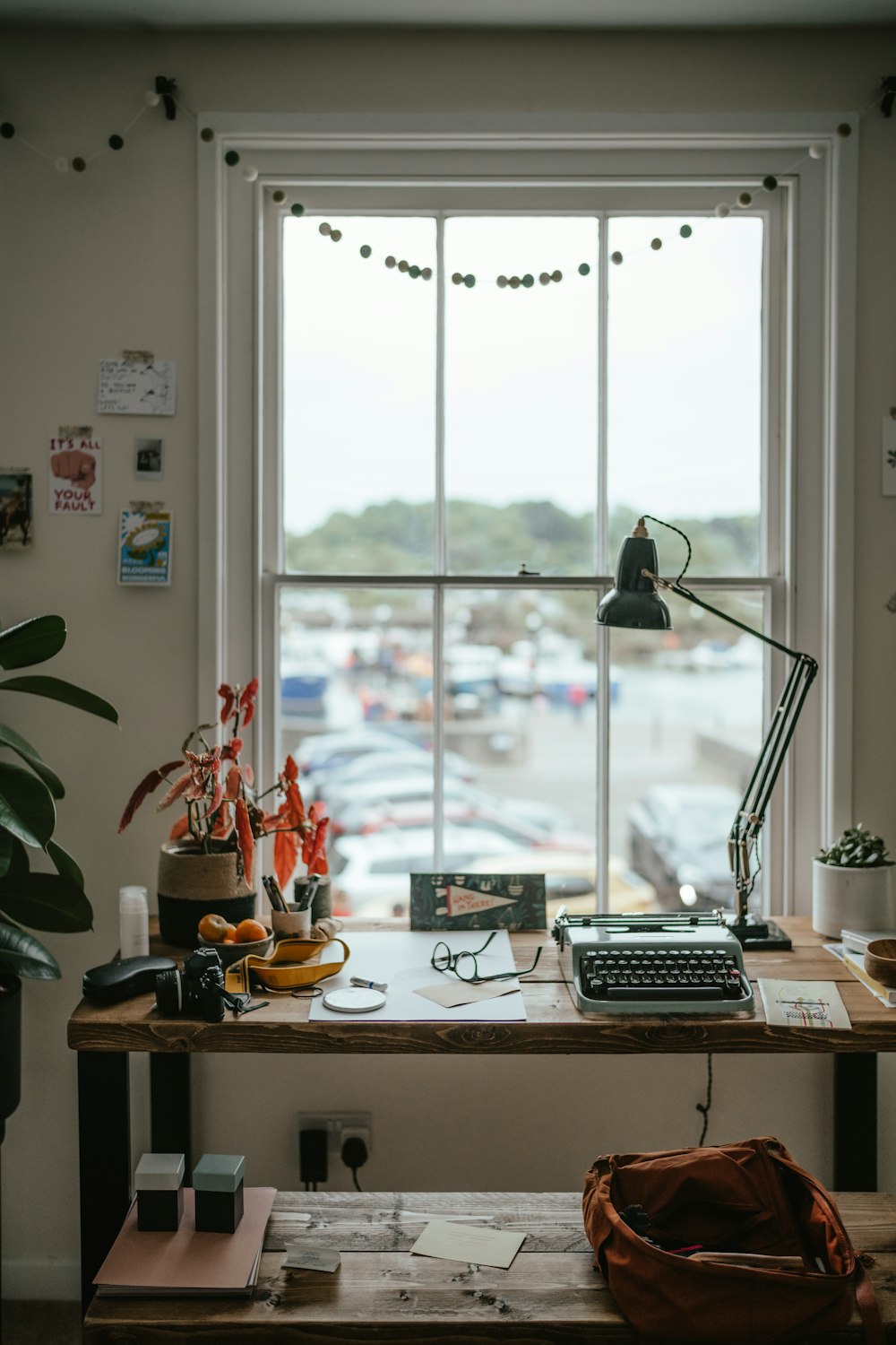 a desk in front of a window with a computer on it