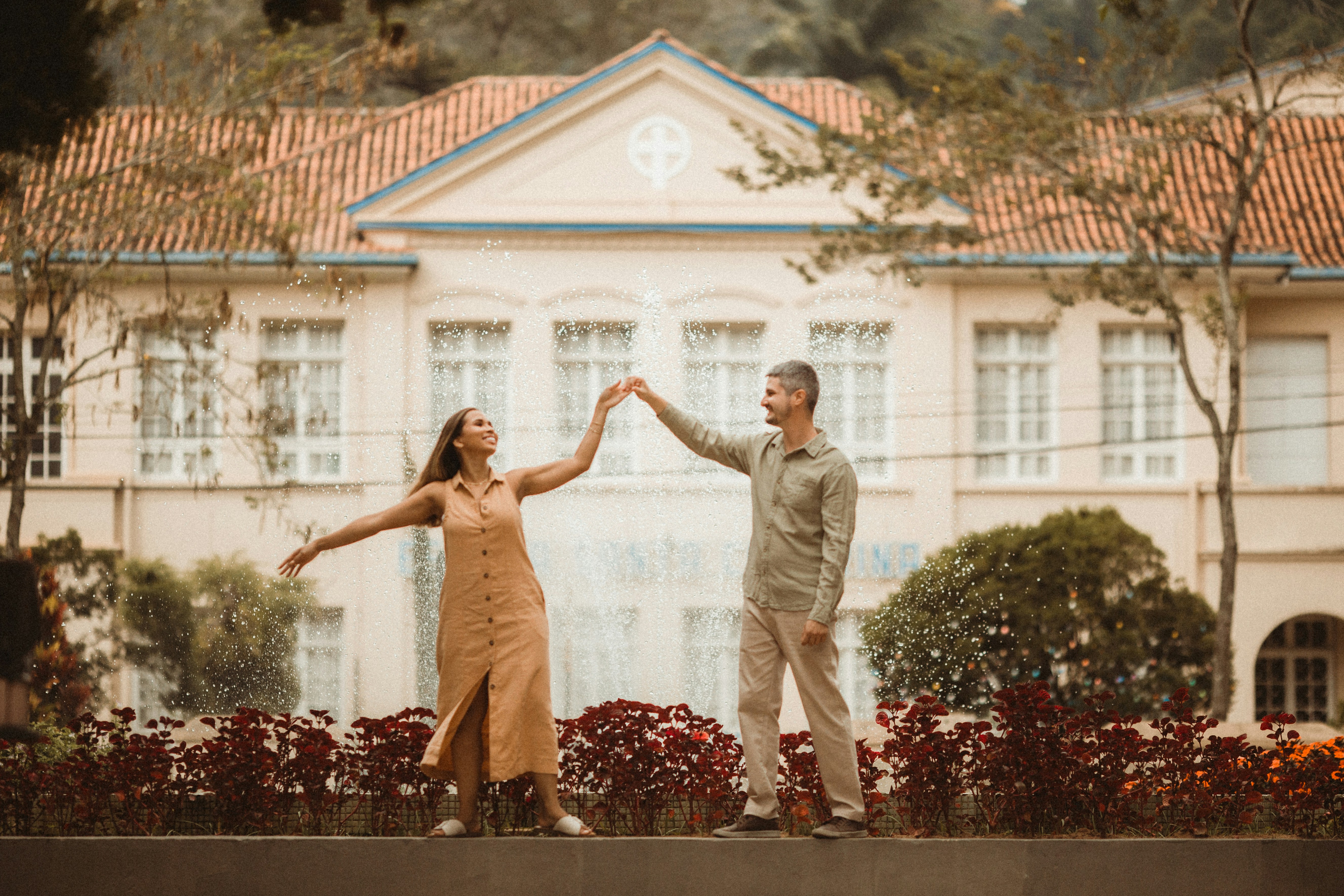 A joyful couple smiles warmly as they hold up the keys to their new home, standing proudly on the porch in front of their front door, celebrating a successful purchase.