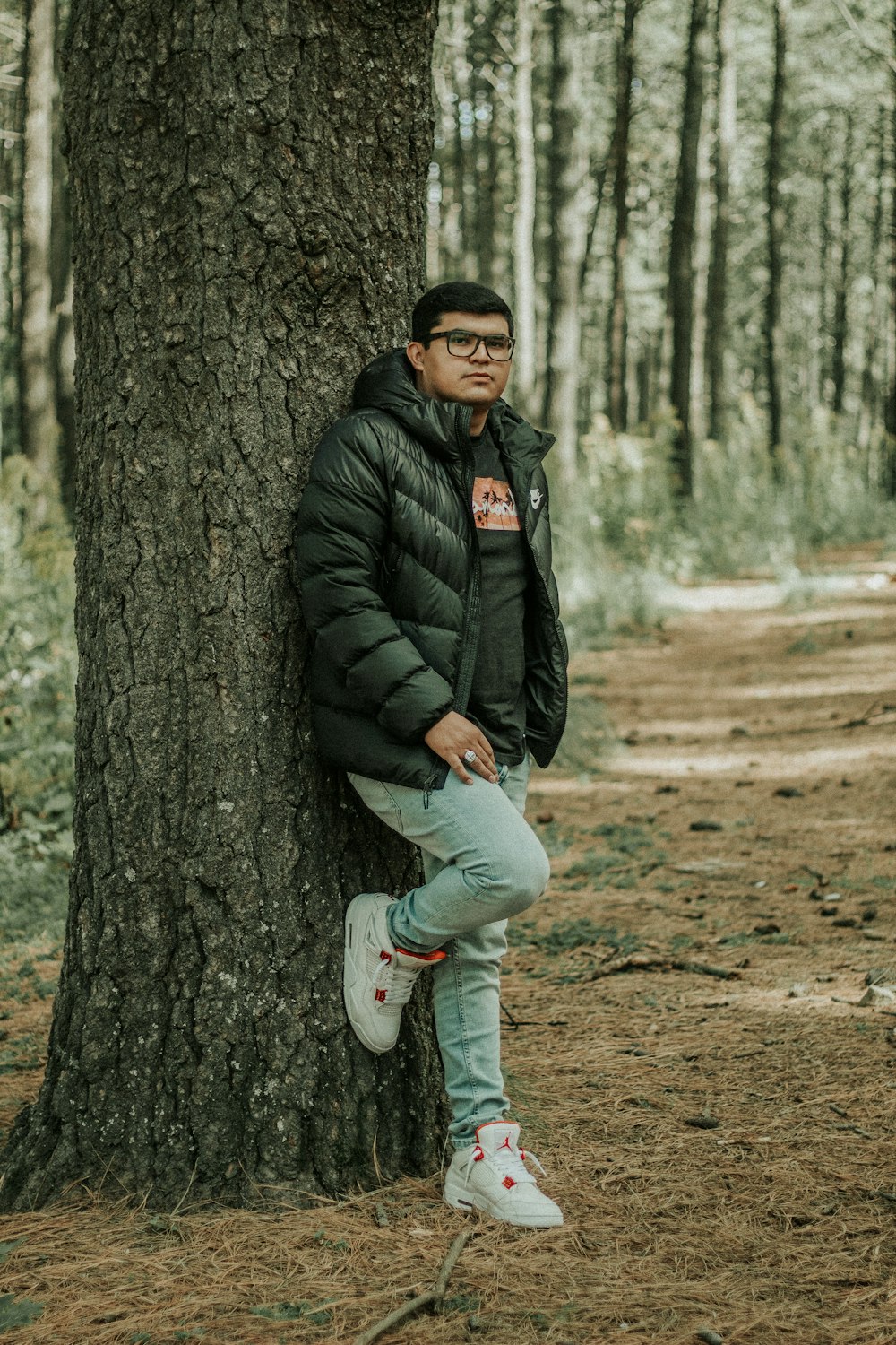 a man leaning against a tree in the woods