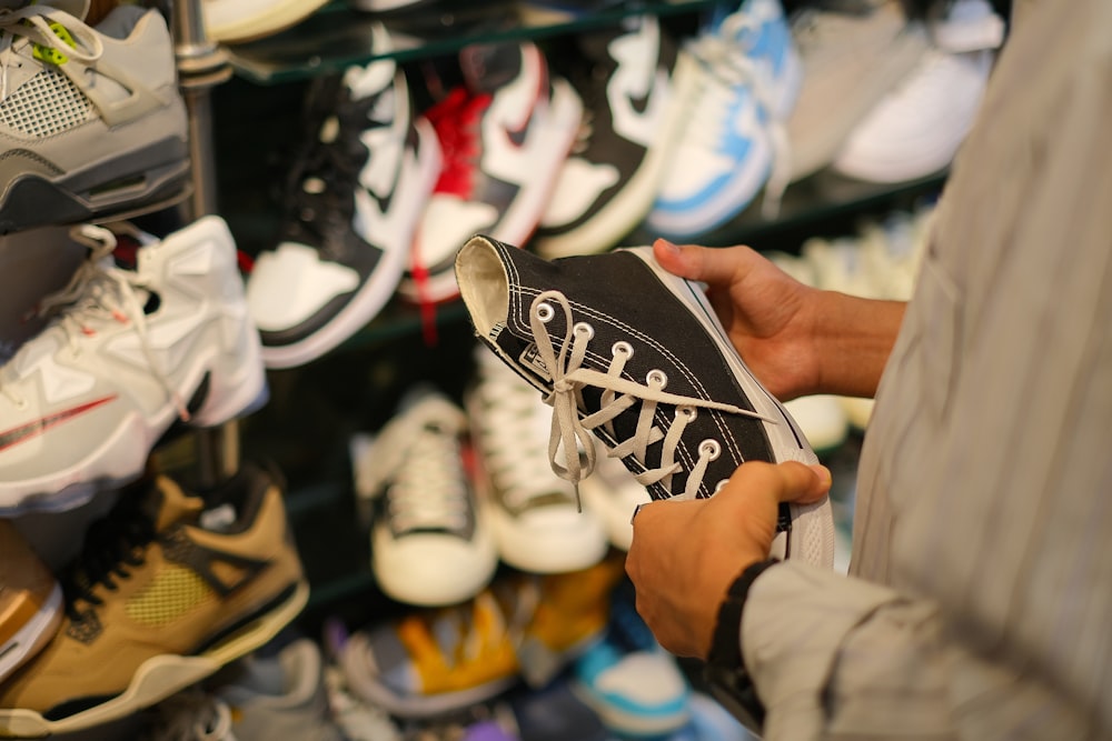 a man holding a pair of black and white sneakers