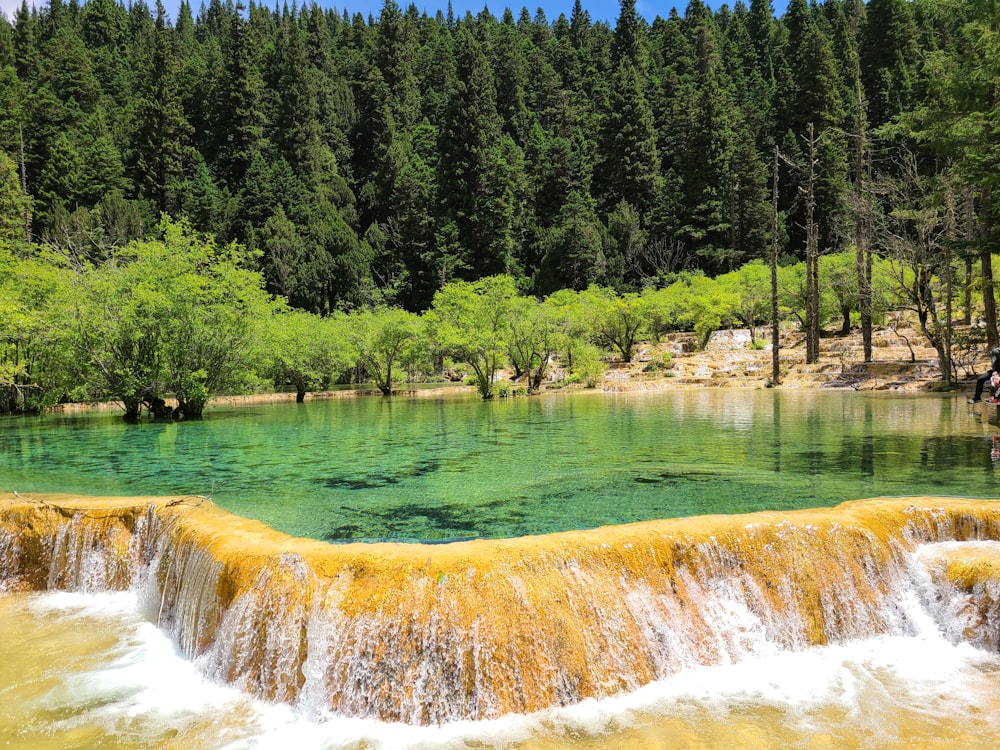 a man is standing in the water near a waterfall