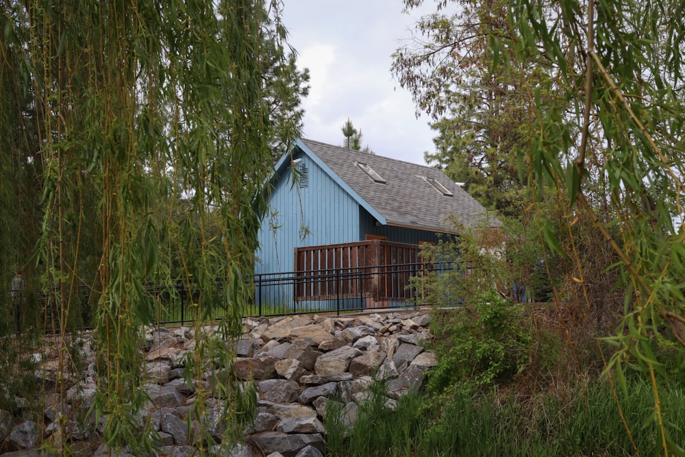 a blue house surrounded by trees and rocks