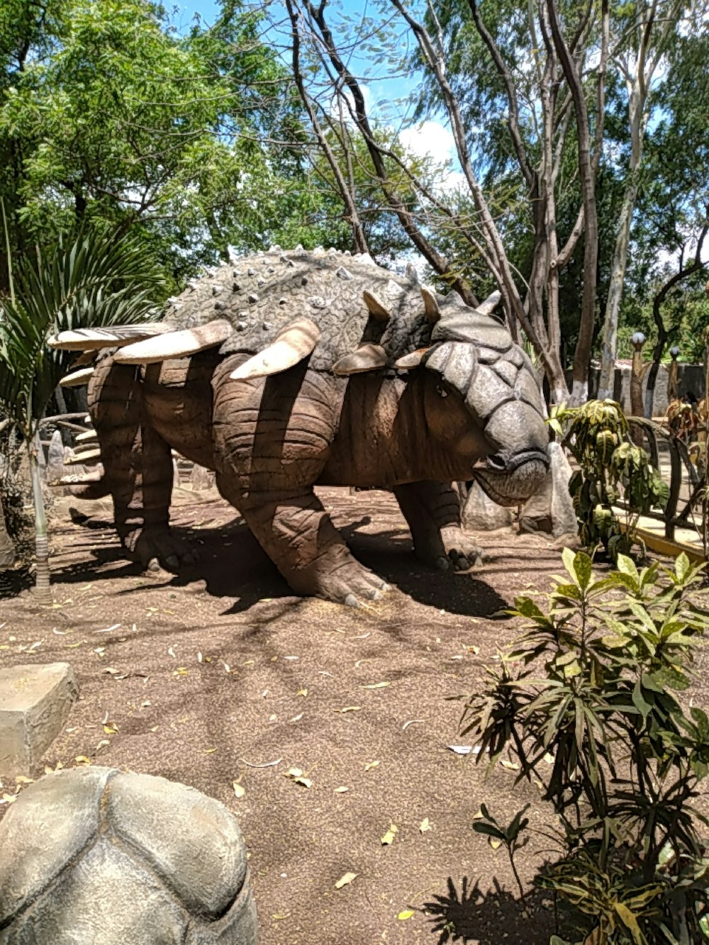 a wooden rhinoceros in a zoo enclosure