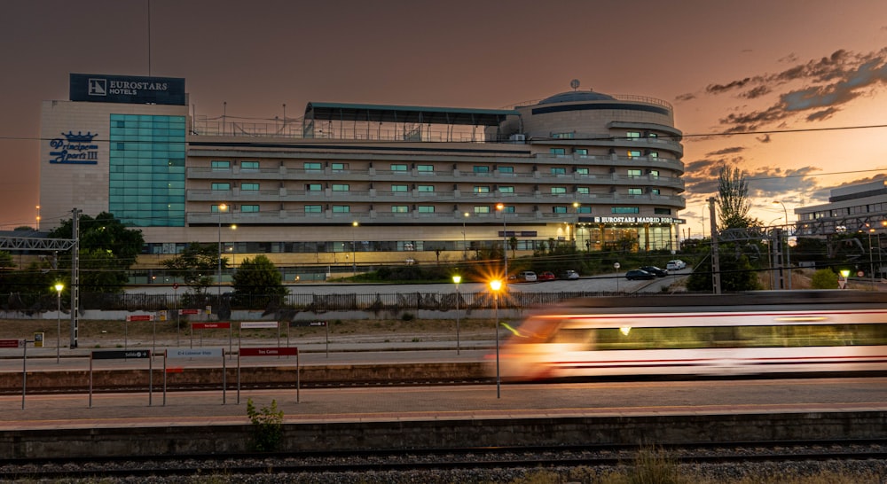 a train traveling past a tall building at dusk