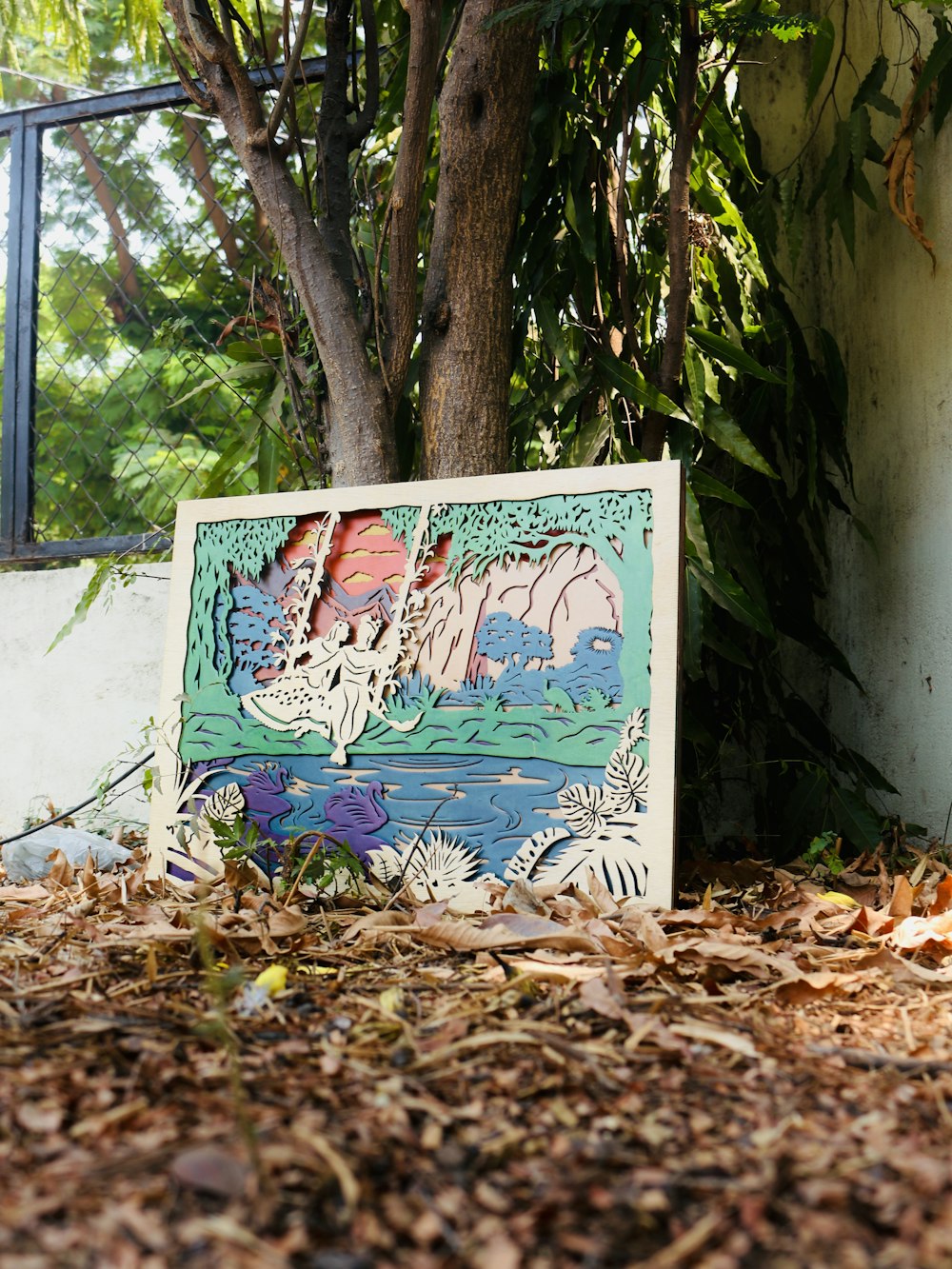 a picture of a painting on the ground next to a tree