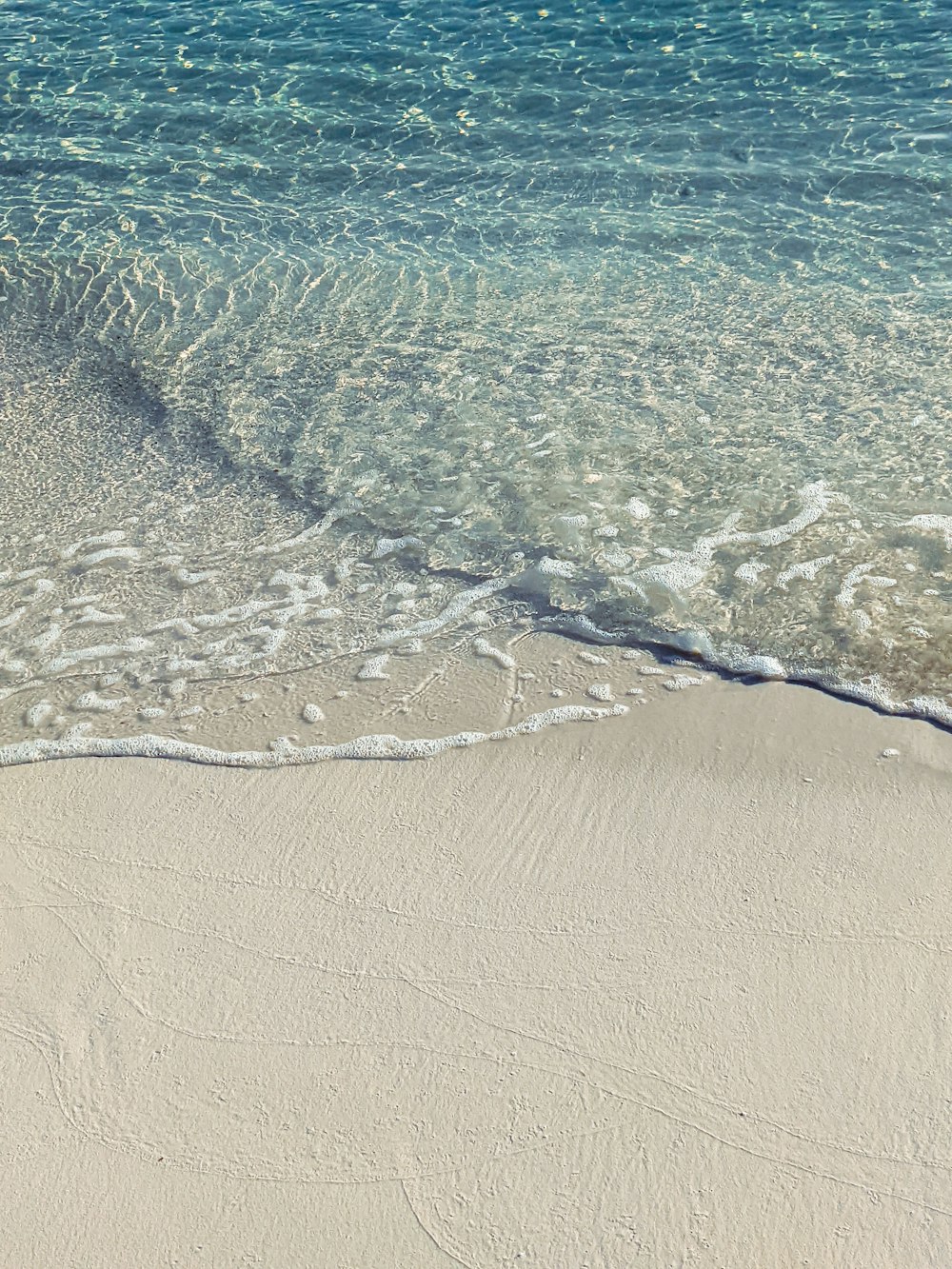 a sandy beach with a wave coming in to shore