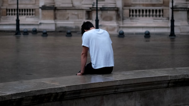 a man sitting on a ledge in front of a building by Mathias Reding (@matreding)