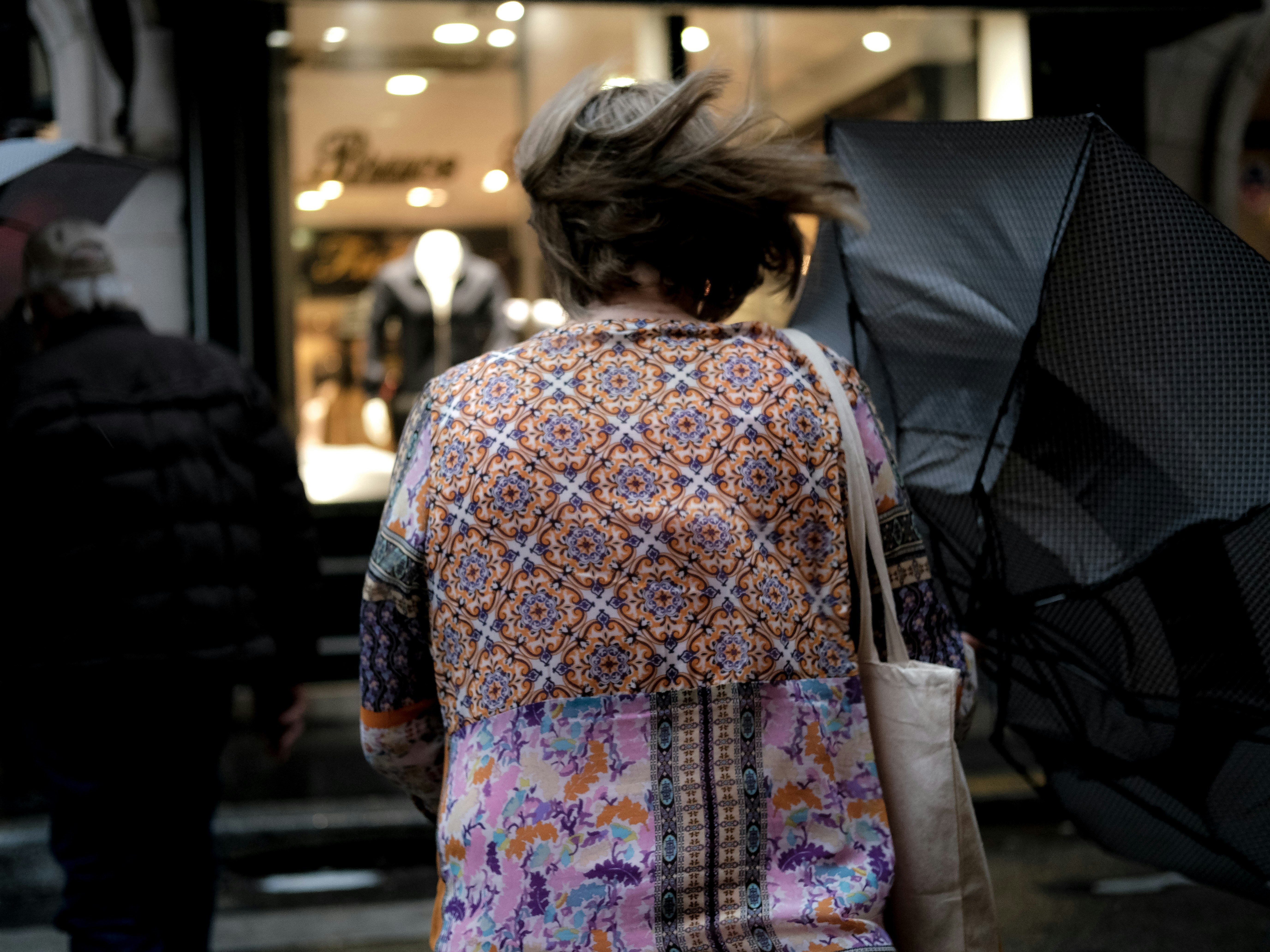 a woman walking down a street holding an umbrella