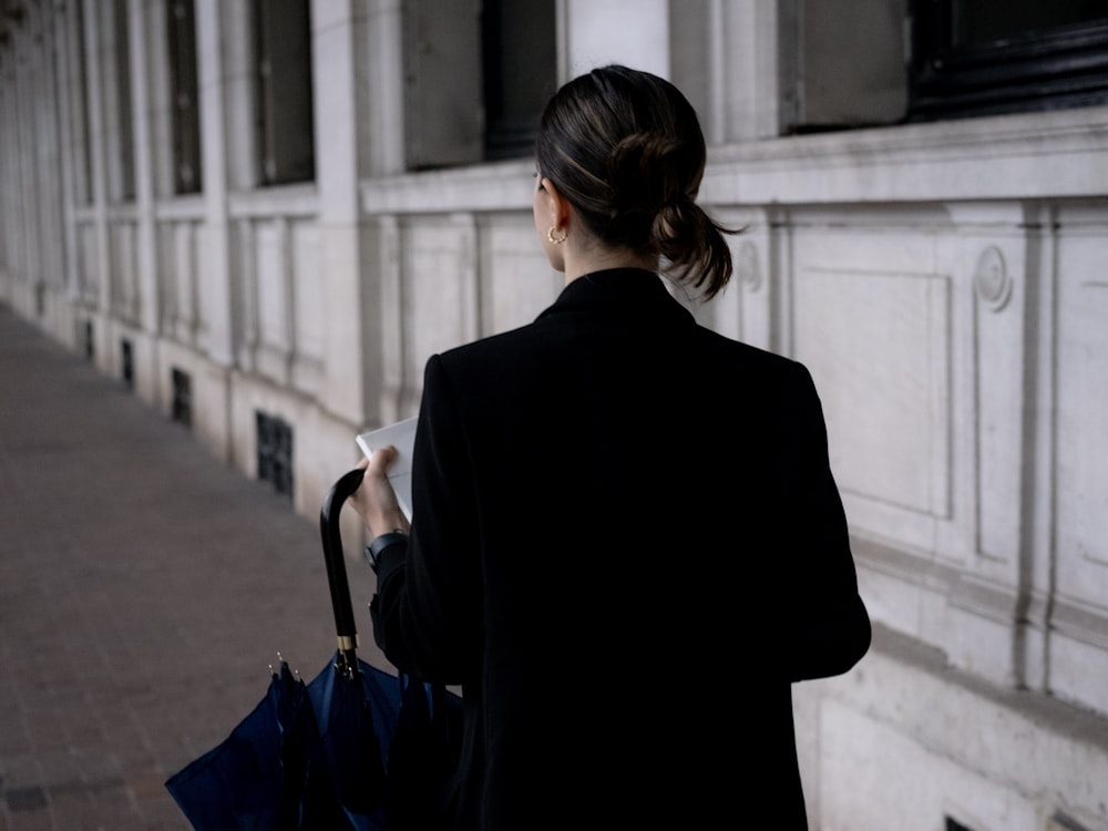 a woman walking down a street holding a blue umbrella