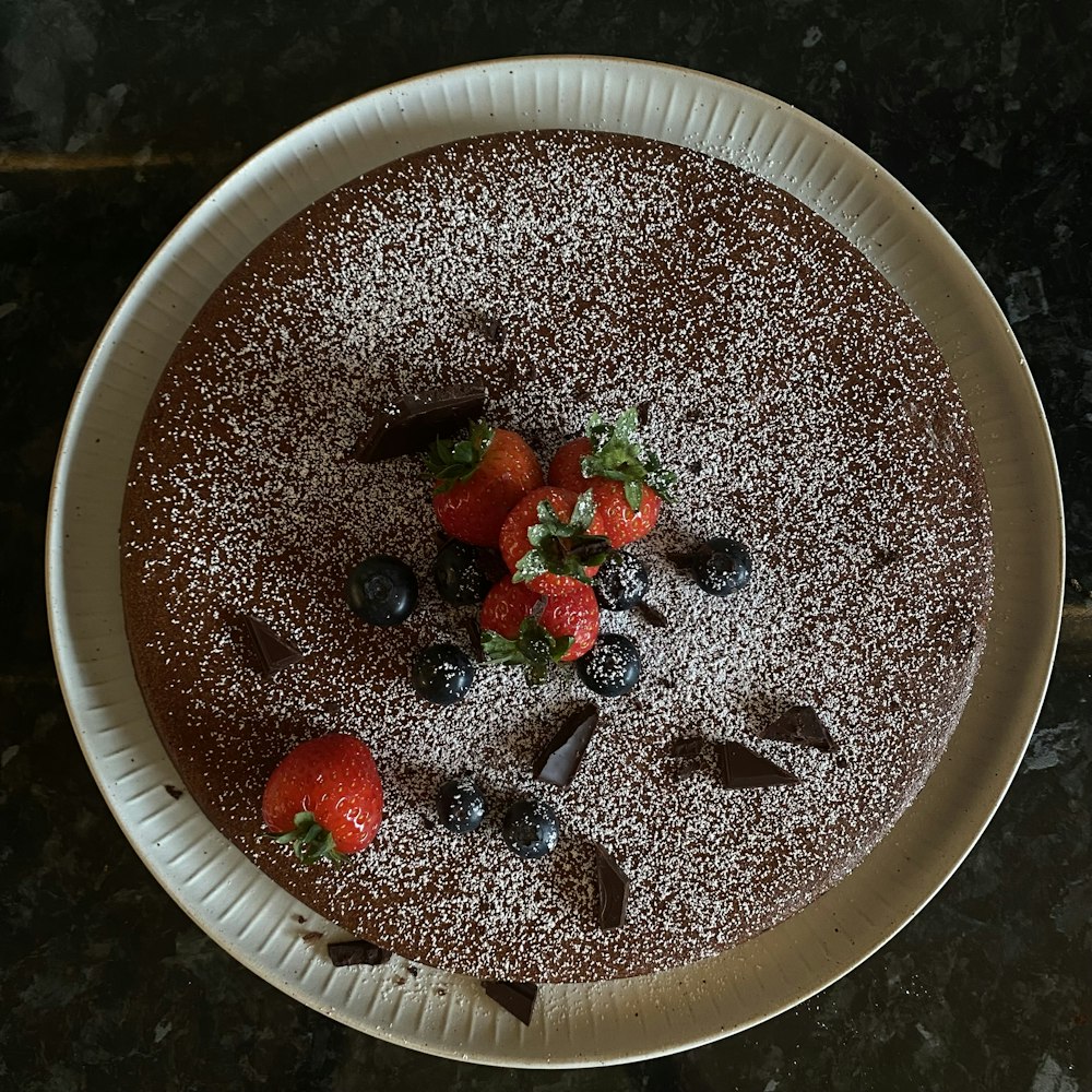 a chocolate cake with strawberries and blueberries on top