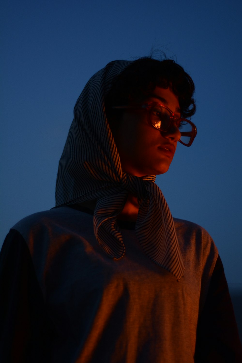 a person wearing a hoodie and glasses at night