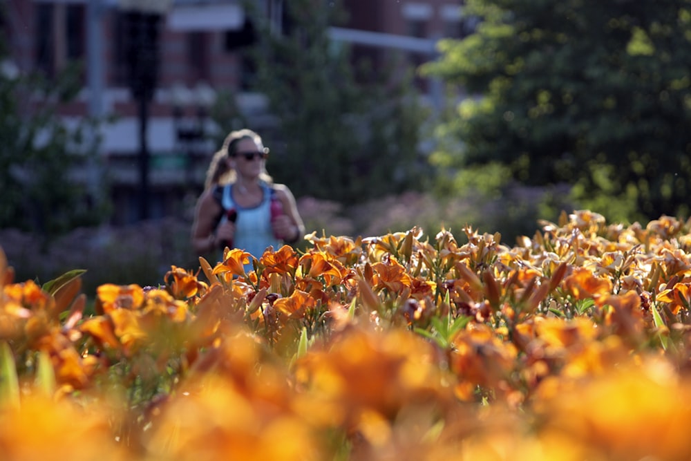 a woman walking through a field of orange flowers