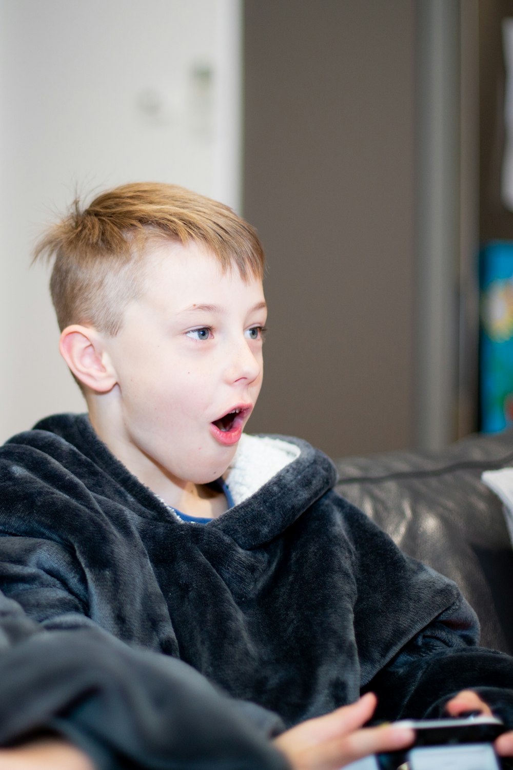 a young boy sitting on a couch holding a remote control