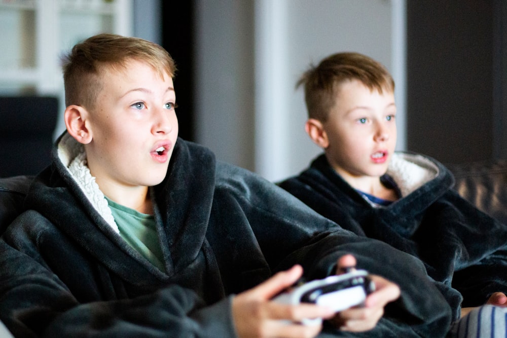 two young boys sitting on a couch playing a video game