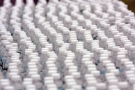 Rows of identical plastic water bottles are closely arranged, creating a pattern of white caps against clear bottles. The bottles are tightly packed, emphasizing uniformity and mass production.