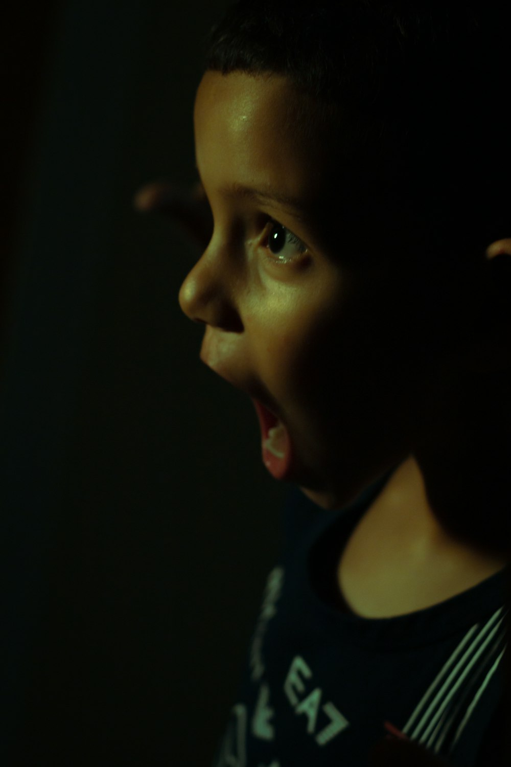 a young boy with his mouth open in the dark