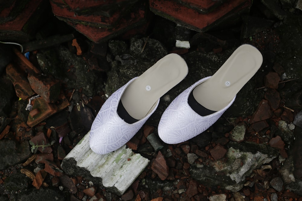 a pair of white slippers sitting on top of a pile of rocks