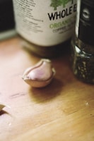 Close-up of a sleek stainless steel garlic press on a wooden countertop.