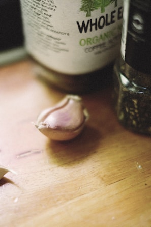 Close-up of a sleek stainless steel garlic press on a wooden countertop.