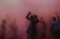 Sunset backdrop with silhouettes of people celebrating with clouds of color powder