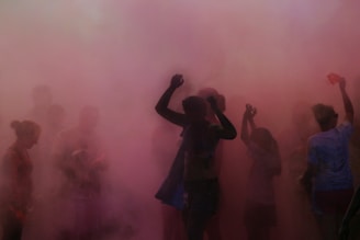Sunset backdrop with silhouettes of people celebrating with clouds of color powder