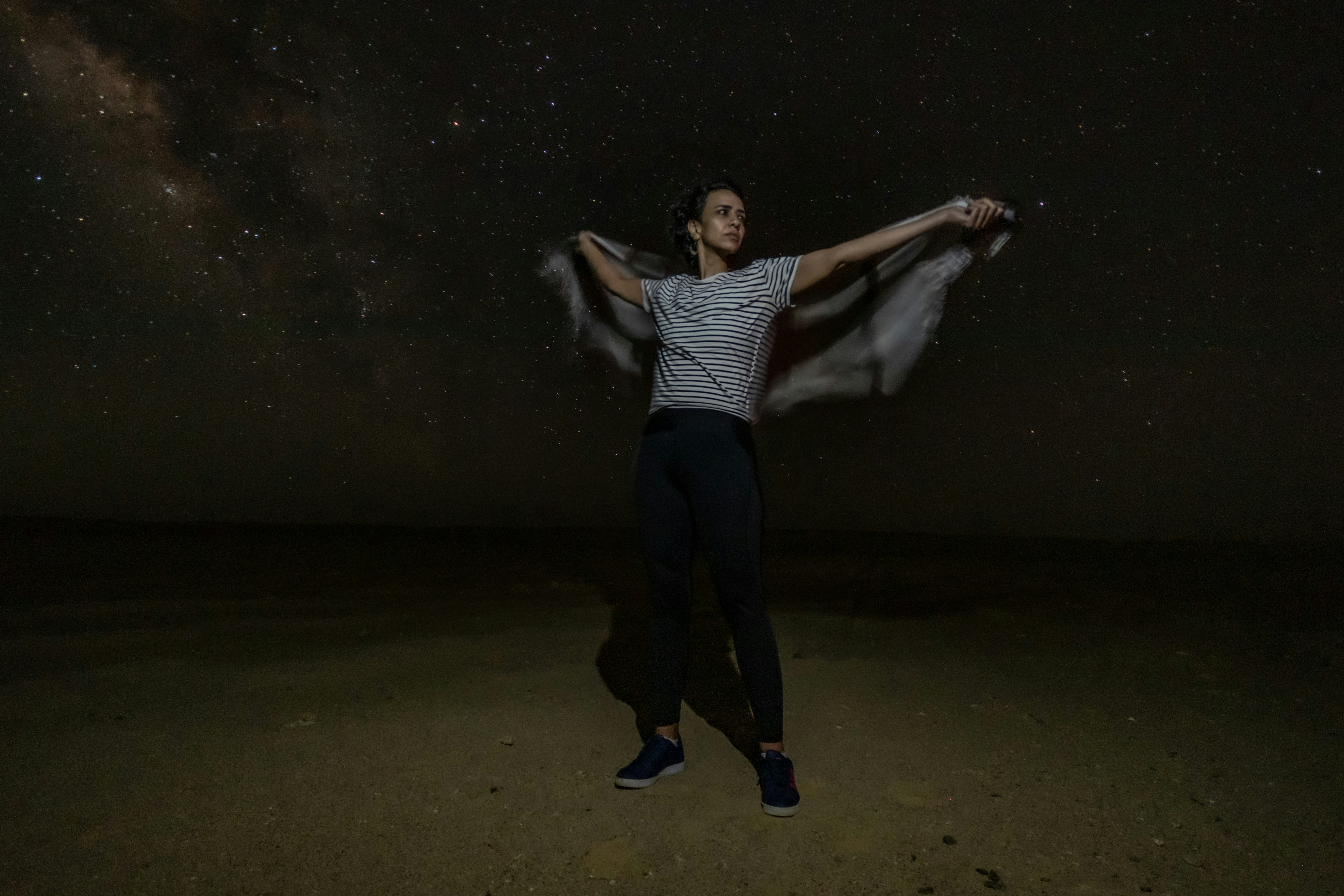a man standing in the middle of a desert under a night sky filled with stars