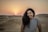 a woman standing in the middle of a desert