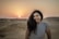 a woman standing in the middle of a desert
