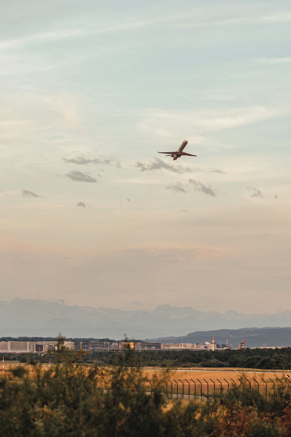 Un aereo che sorvola un campo con le montagne sullo sfondo