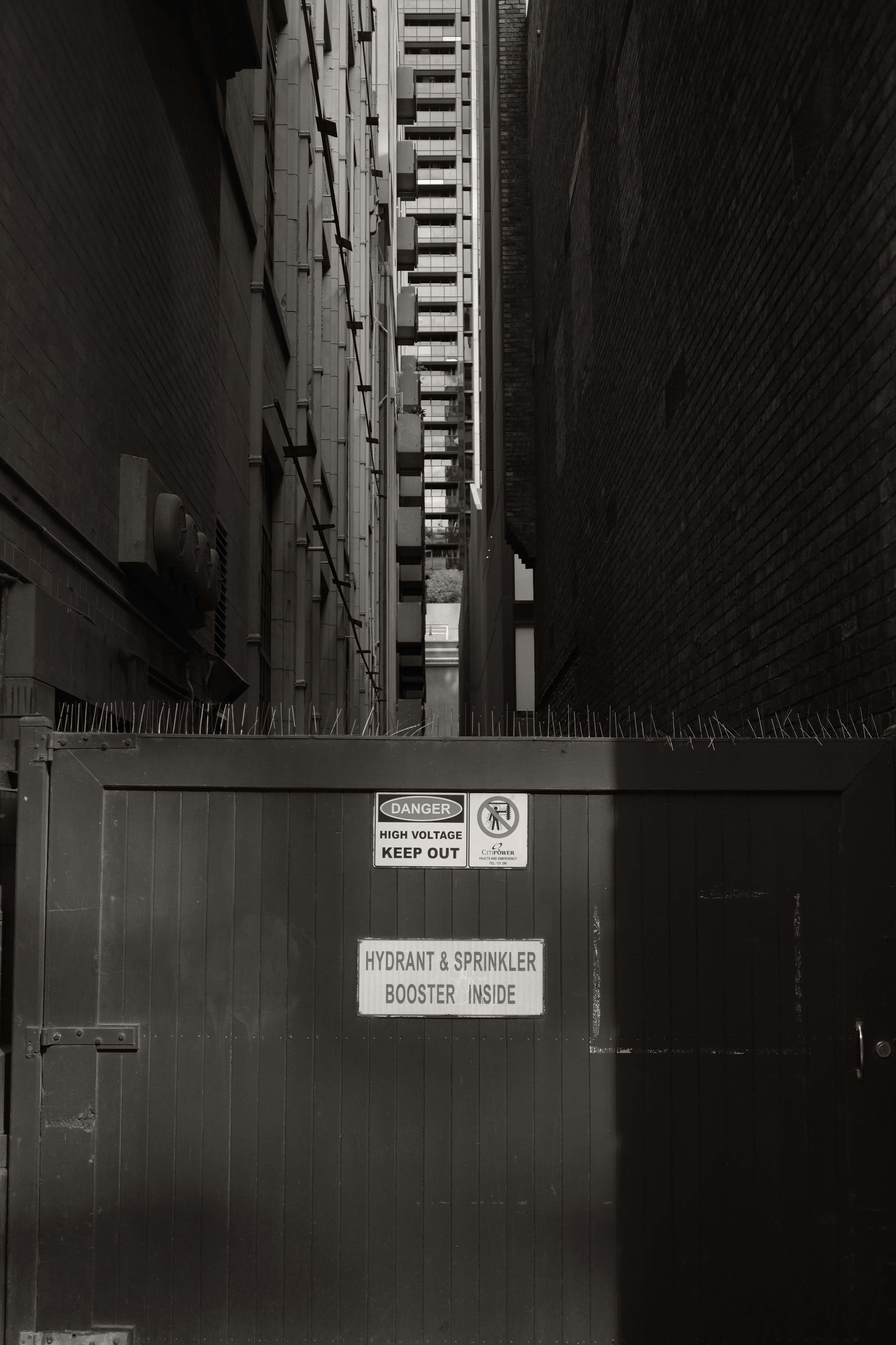A bright ray of sunlight highlights warming signs blocking the entry to a city alleyway