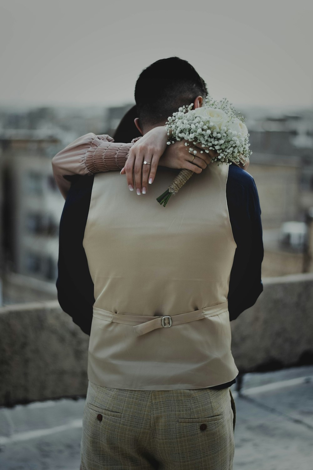 a man holding a bouquet of flowers on top of a roof