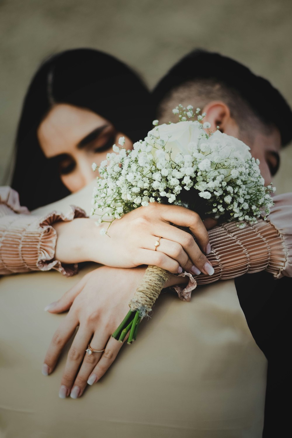 a man and a woman hugging each other and holding a bouquet of flowers