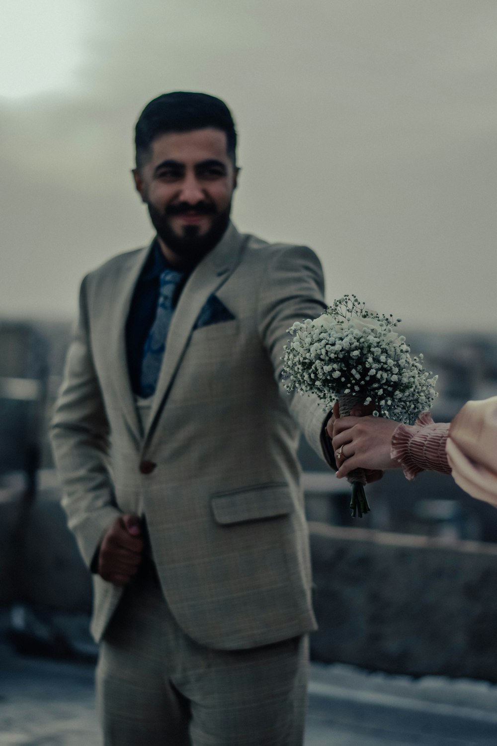 a man in a suit holding a bouquet of flowers