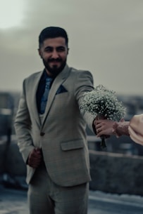 a man in a suit holding a bouquet of flowers