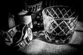 Artful black and white shot of refined lifestyle details: a wristwatch on a cuff, textured fabrics.