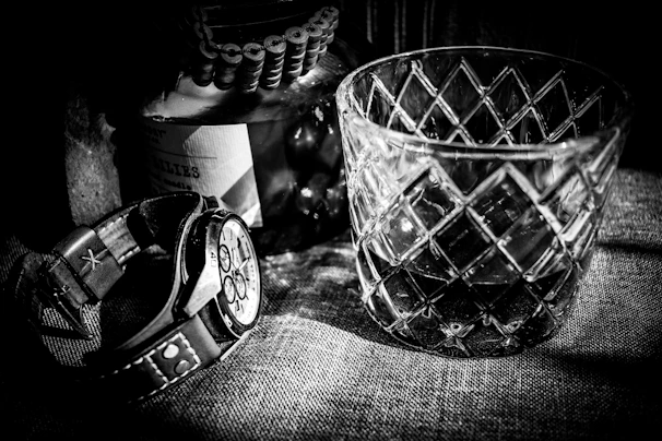 A detailed shot of a watch and sunglasses styled on a neutral-toned background.