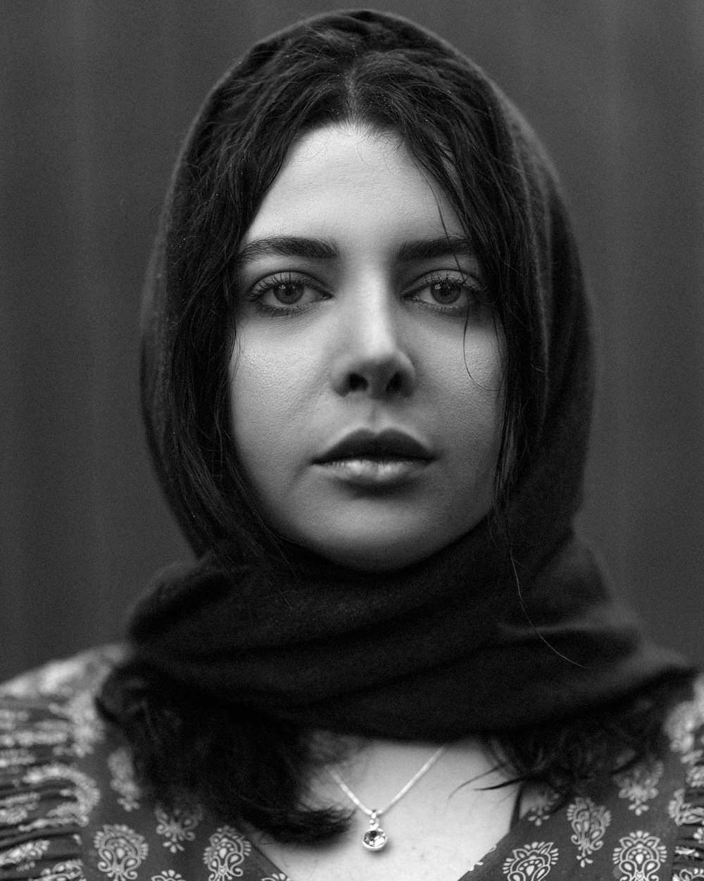 a black and white photo of a woman wearing a scarf
